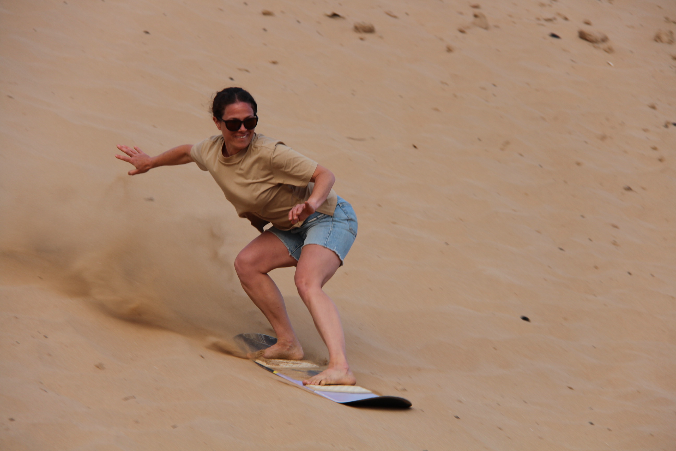 Woman sandboarding on desert dunes